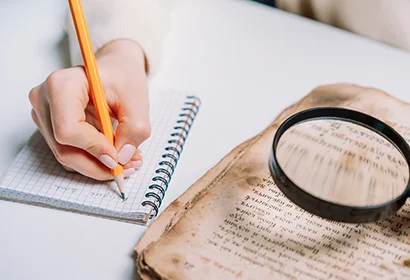 Person writing in a book with a pencil.